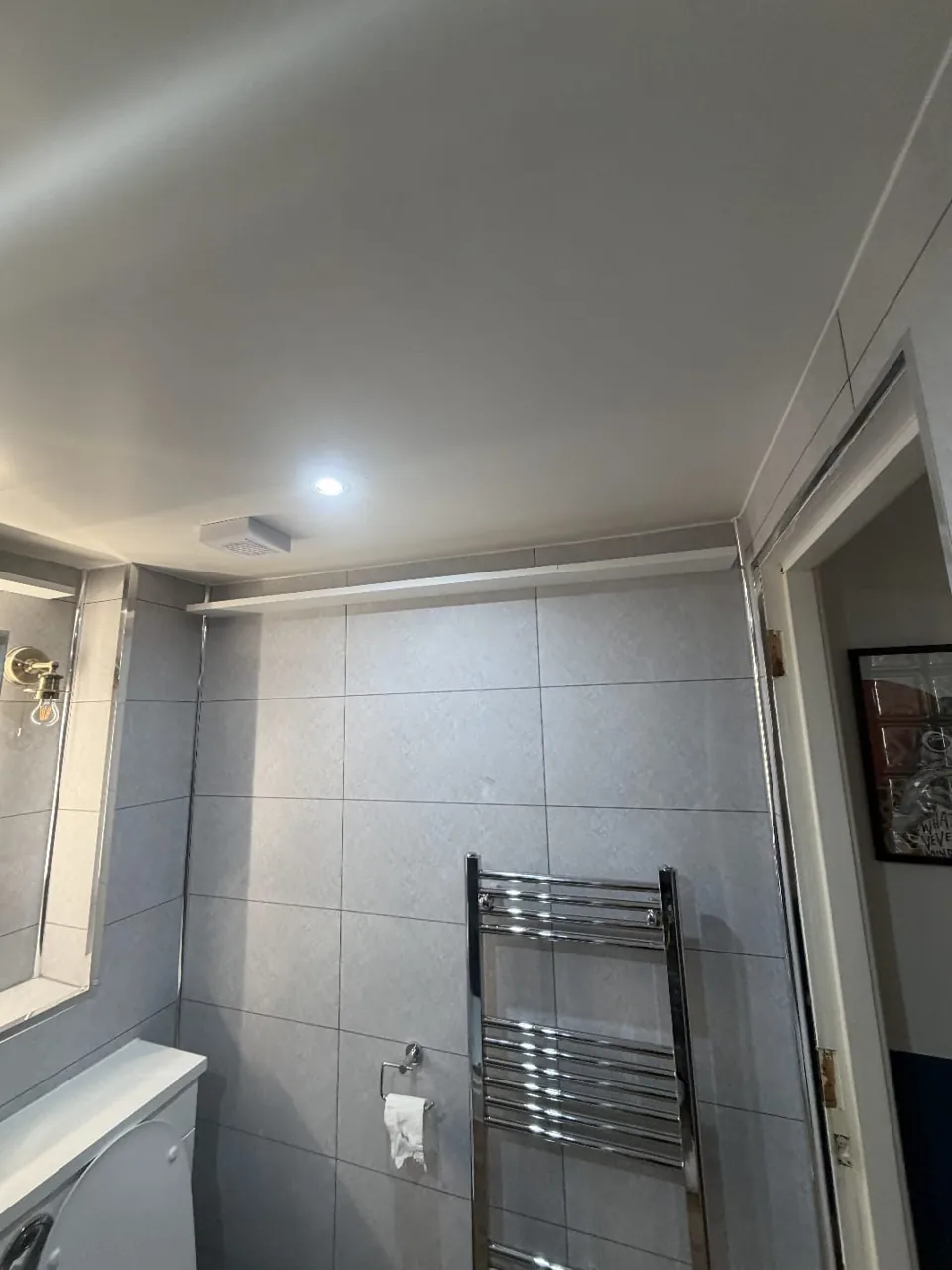 White bathroom furniture and a large illuminated mirror